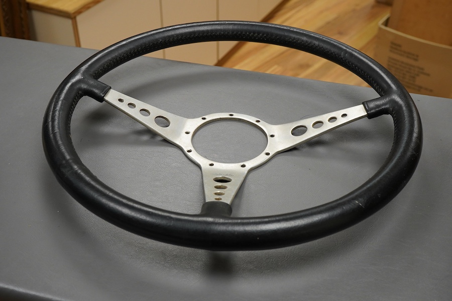 Racing ephemera, including; a Moto-lite steering wheel, a driver's leather cap, an enamelled Le Mans pilot’s radiator badge, signed photograph of Prince Michael Kent standing next to a 12 cylinder single seat racing car